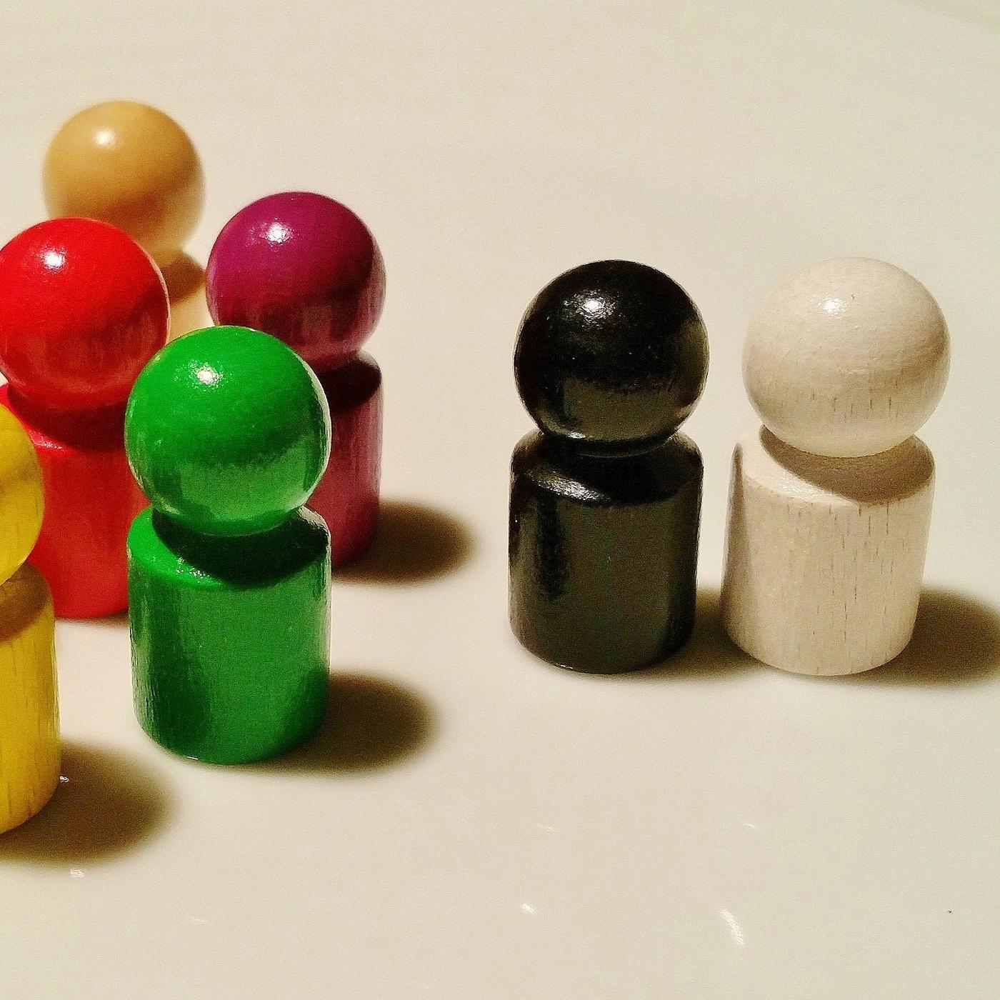 Ein schwarzer und ein weißer Spielstein stehen abseits der bunten Spielsteine.